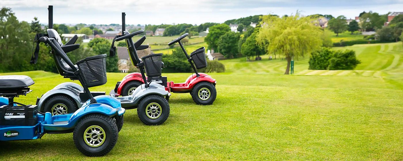Bugg-Ease electric golf buggies in blue, silver and red parked on a sunny golf course