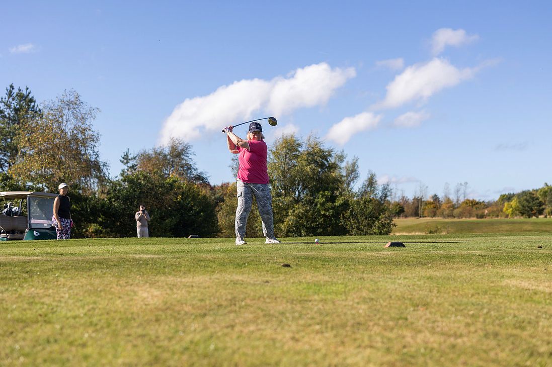 A golfer tees off under a blue sky